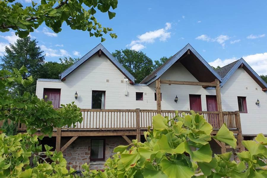 a large white house with a wooden porch at Chambres de séjour et Brasserie du Coiroux in Aubazines