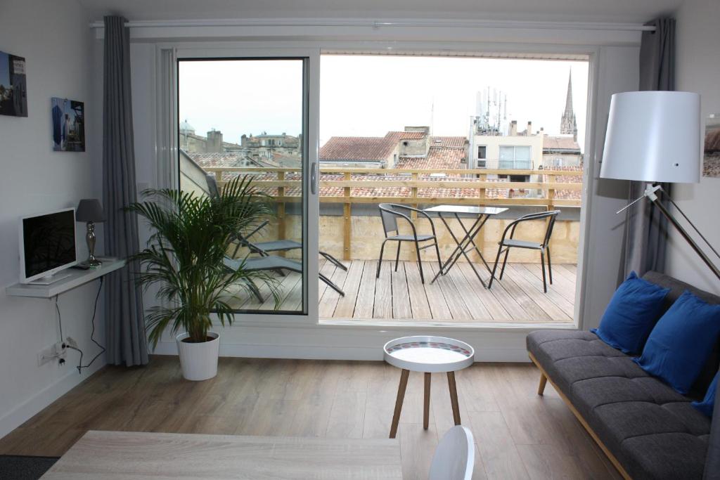a living room with a couch and a balcony with a table at Le Clos Beaufleury in Bordeaux