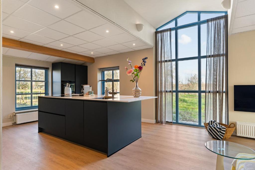 a kitchen with a island in a room with windows at Boerderij appartement 't Vogelnest in Heiloo