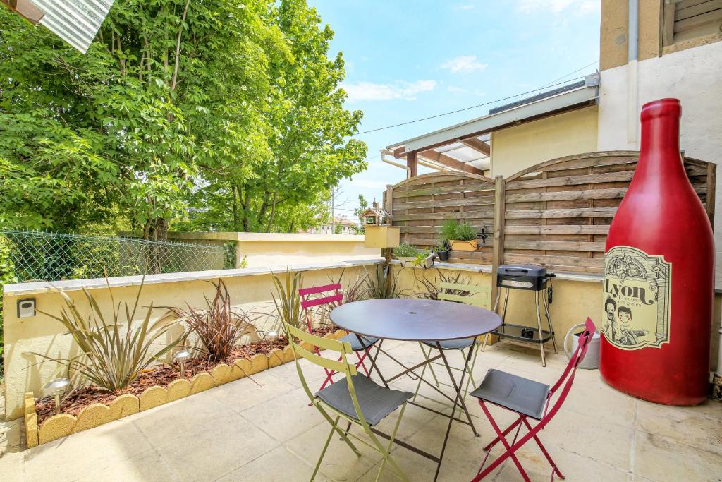 a patio with a table and chairs and a large wine bottle at Maison avec terrasse proche Lyon in Rillieux