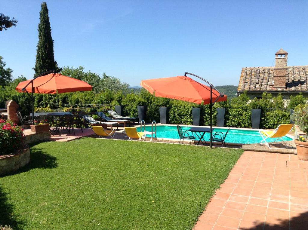 a backyard with a pool and chairs and umbrellas at Casale La Petrosa in Radda in Chianti