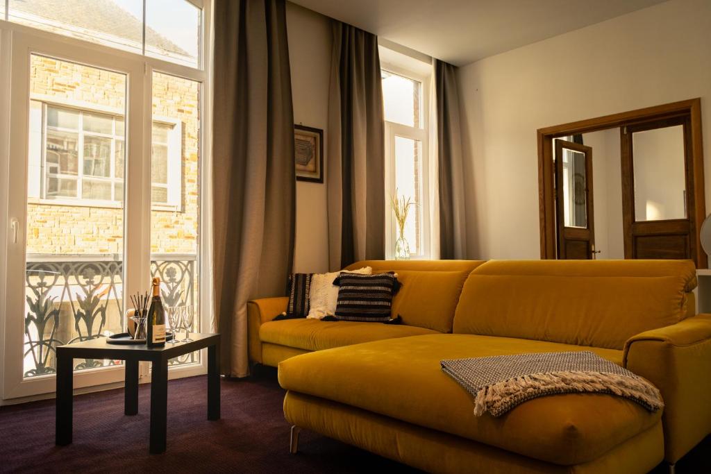 a living room with a yellow couch and a table at Sur un air d'eau in Spa