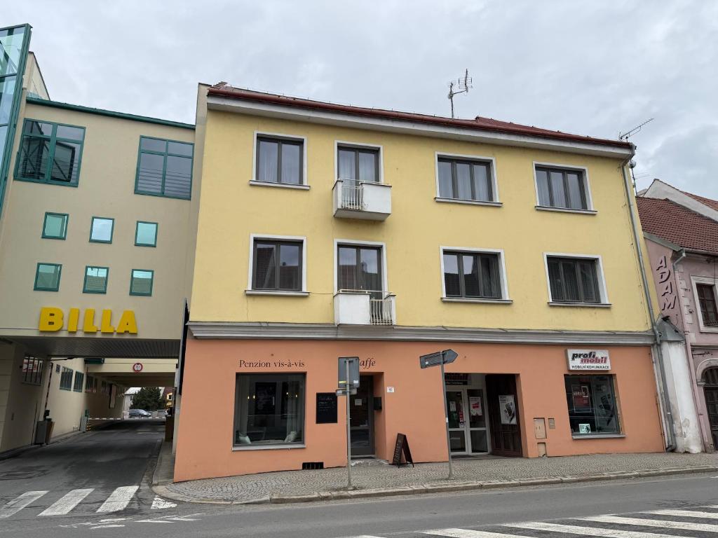a yellow and orange building on the corner of a street at Penzion Vis a Vis in Třebíč