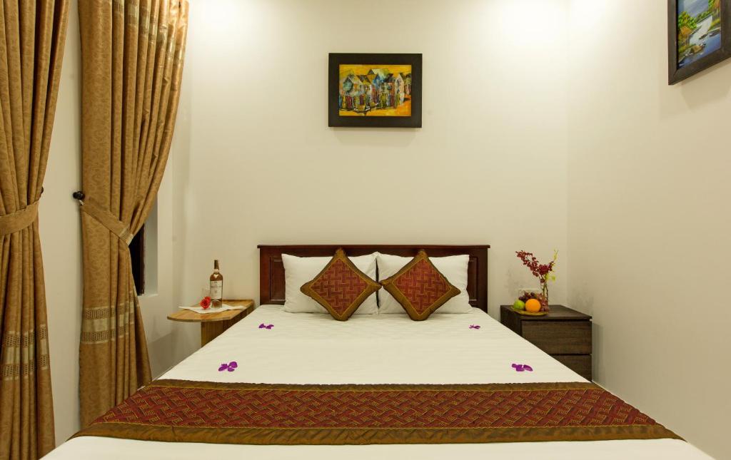 a bedroom with a bed with white sheets and pillows at Golden Bee Homestay in Hoi An