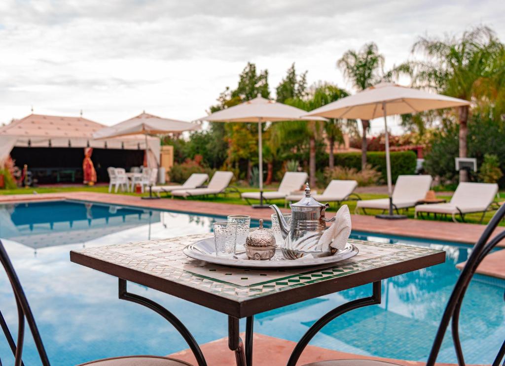 a table with a plate of food on it next to a pool at Bungalow with Pool View & Breakfast in Marrakesh