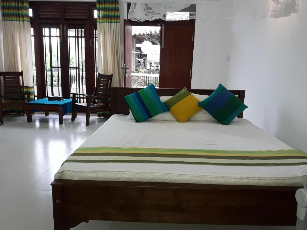 a bedroom with a bed with colorful pillows on it at Majestic Apartments in Nawala