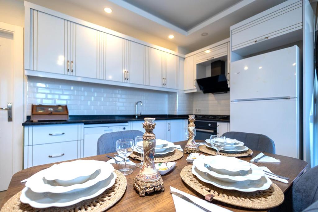 a kitchen with a wooden table with white cabinets at ALANYA KONAKLİ APART in Alanya