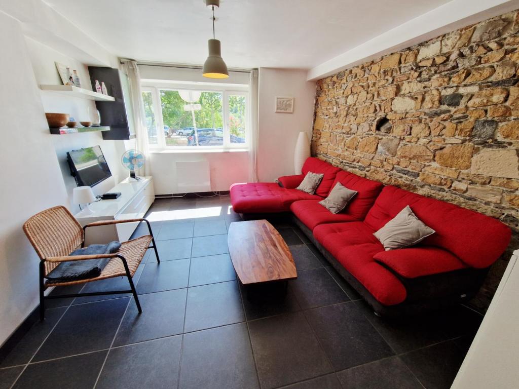 a living room with a red couch and a stone wall at Grand duplex 5 pers au cœur de Lyon Opéra & métro in Lyon