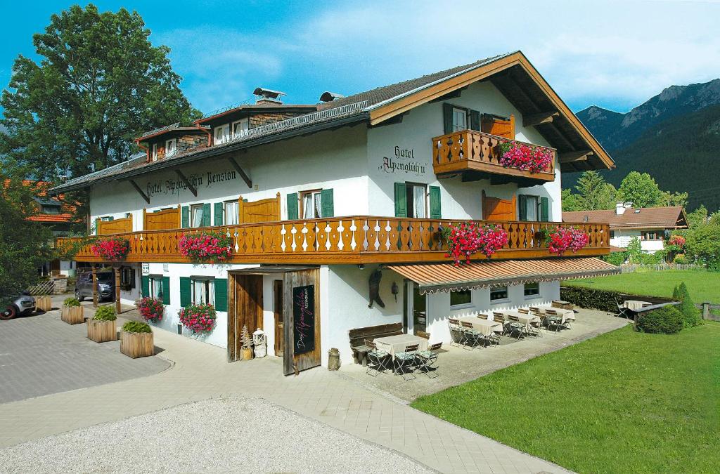 a large building with a balcony and tables and chairs at Das Alpenglühn Hotel & Restaurant in Krün