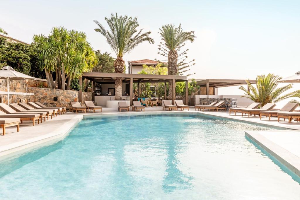 a swimming pool with lounge chairs and a resort at Casa Elounda - Adults only Hotel "by Checkin" in Agios Nikolaos