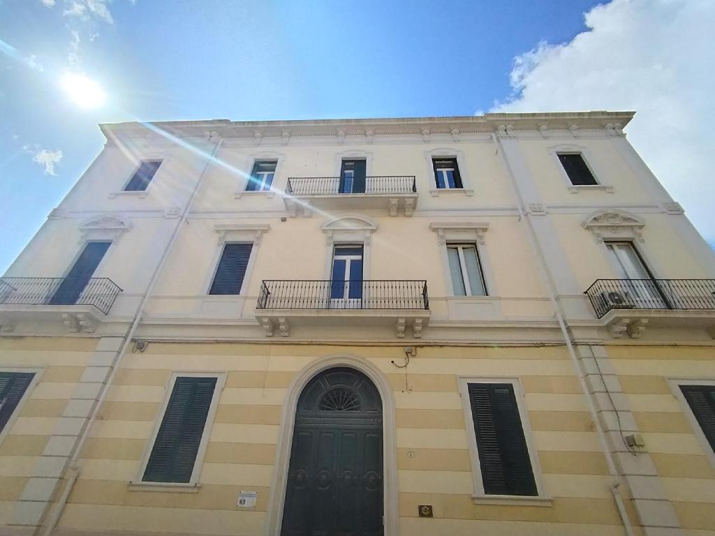a tall white building with a green door at Palazzo Castellano in Lecce