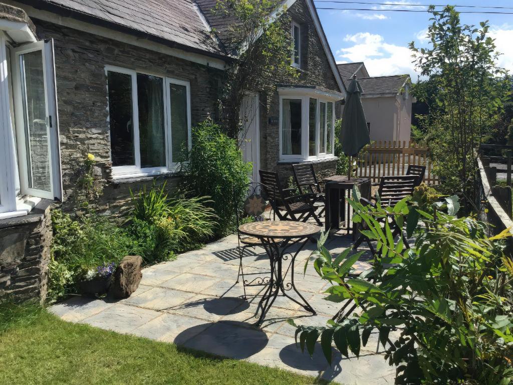 a patio with chairs and a table in front of a house at Glanyrafon Smithy in Llandysul