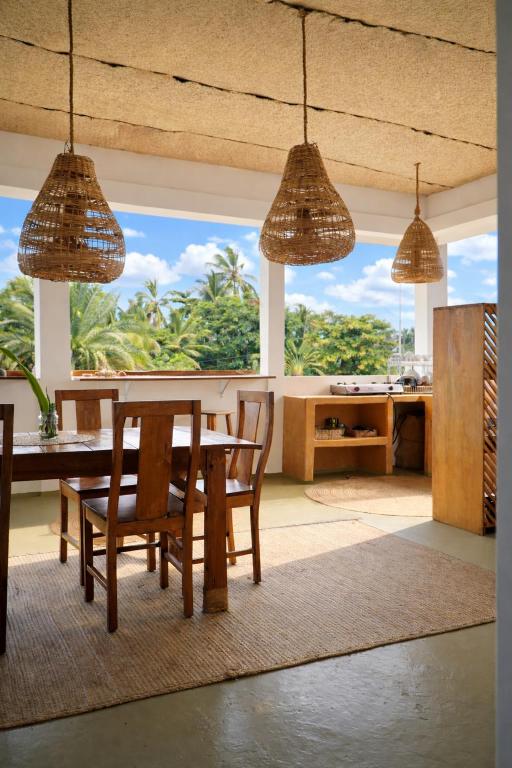 a dining room with a table and chairs and a large window at Mlango Paje House II in Paje