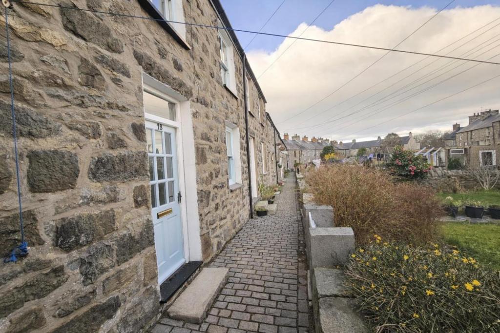 a stone house with a white door and a brick sidewalk at Pen Llyn Quarryman's Cottage in Trevor