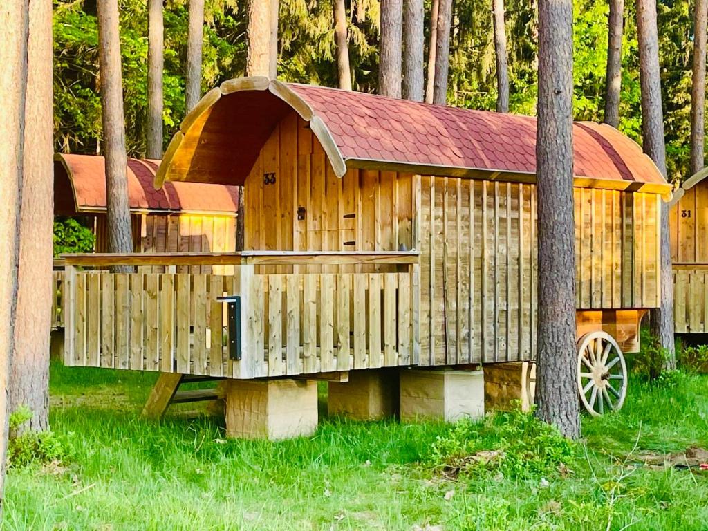 a wooden play house in the middle of trees at NATURAMA Brombachsee Schäferwagenhotel in Pleinfeld