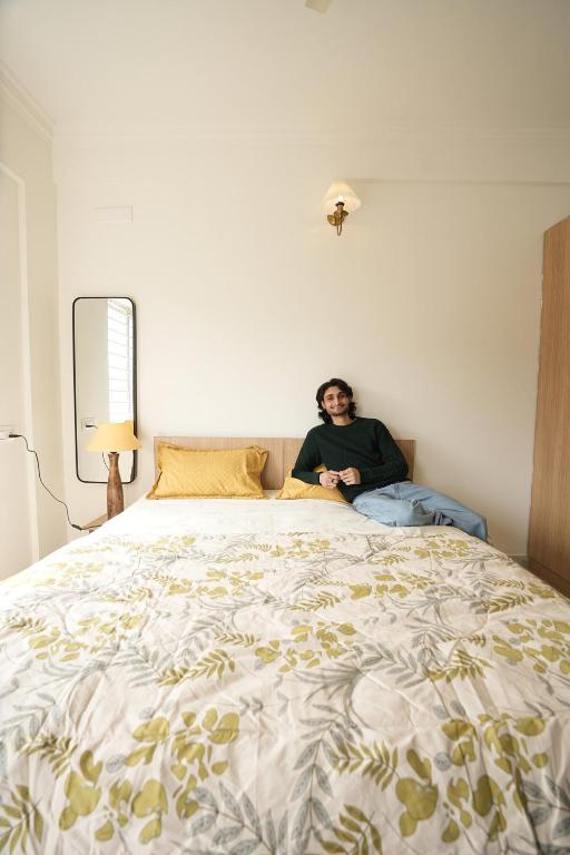 a man sitting on top of a large bed at HomeSlice Sarjapur - Balcony Rooms in Bangalore