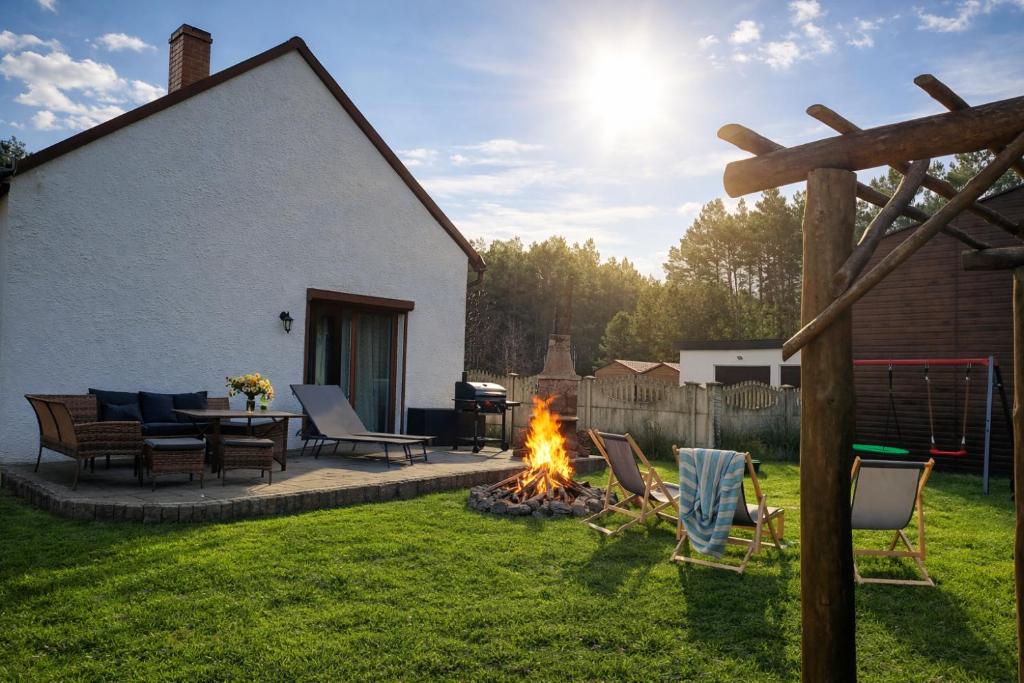 a fire pit in a yard with chairs and a table at Leśny Domek in Piłka