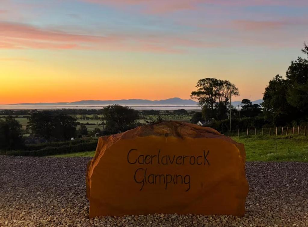 a rock sitting on the ground with the sunset in the background at Caerlaverock Glamping - Sycamore in Dumfries