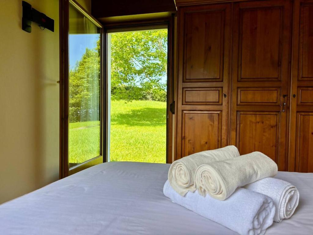 a bedroom with a bed with rolled towels and a window at Chalet con jardín junto a playas in Colunga