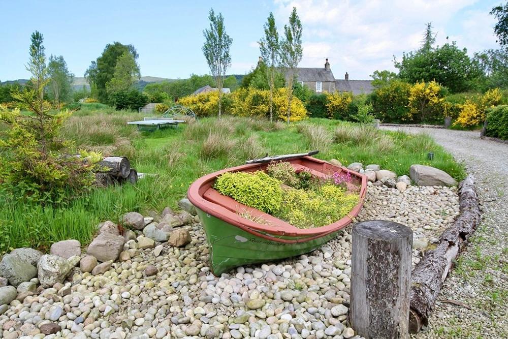 a green boat sitting on a pile of rocks at Byre 2 In The Park in Callander