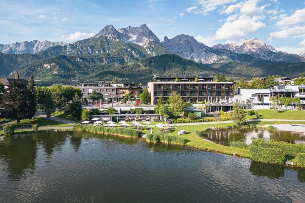 a resort with a lake and mountains in the background at Ritzenhof - Hotel und Spa am See 4-Sterne-Superior in Saalfelden am Steinernen Meer