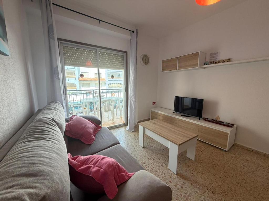 a living room with a couch and a table and a television at Wimpy Solo Familias Serviplaya in Playa de Xeraco
