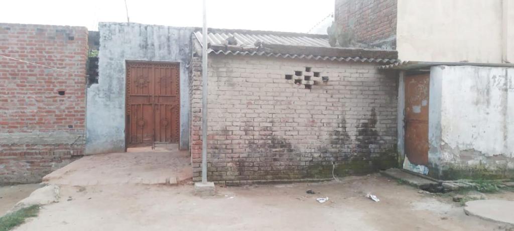 a brick building with a gate and a door at Dwivedi Nivas in Banda