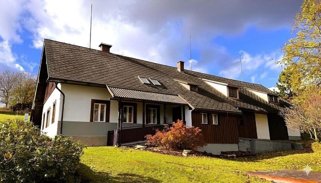 a white and brown house with a grass yard at Chalupa Lindenberg in Jestrabi V Krkonosich