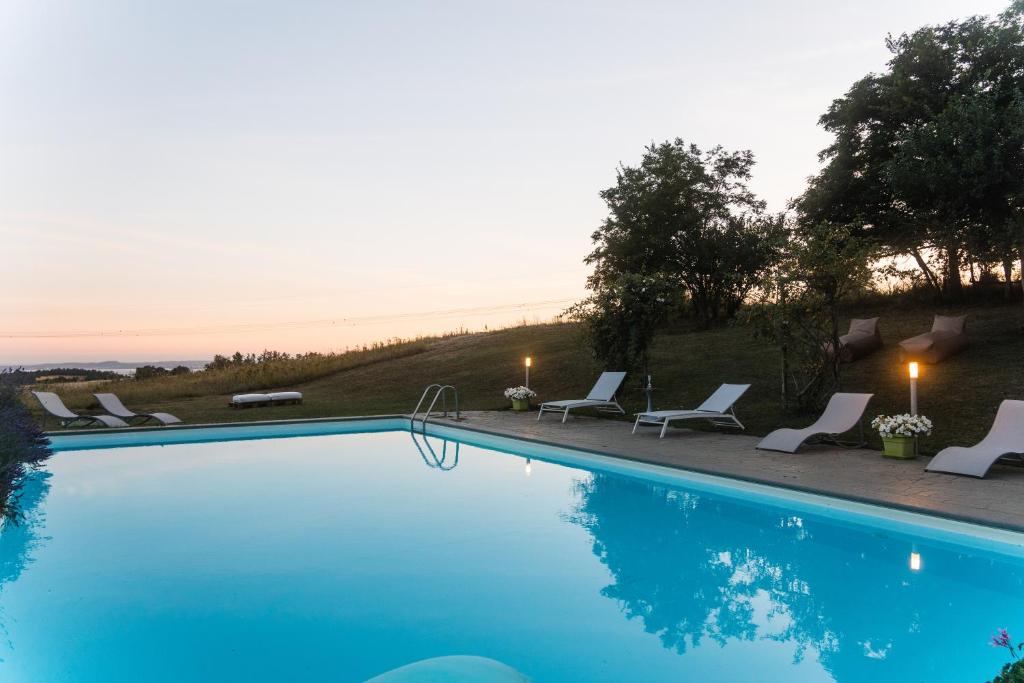a blue swimming pool with chairs and a sunset at CollinaBlu in Torre San Severo