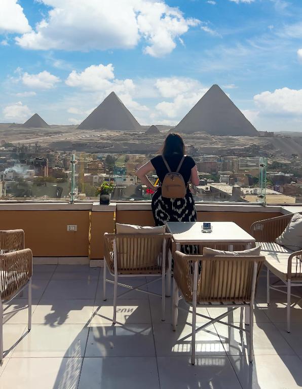 a woman sitting at a table looking out at the pyramids at panorama pyramids view inn in Cairo