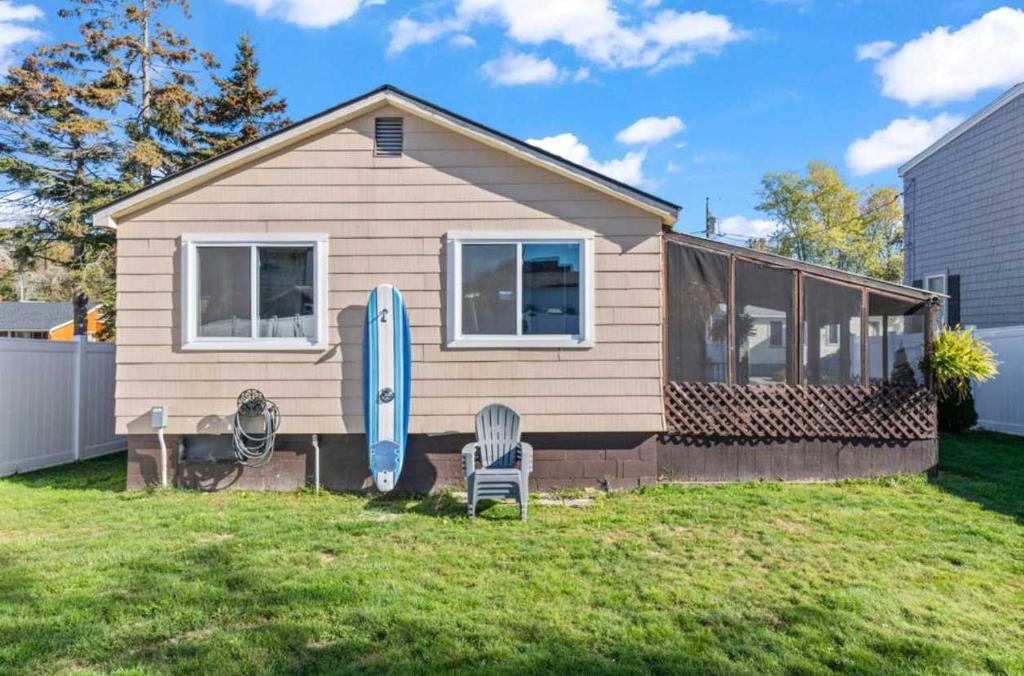 a house with a surfboard and a chair in the yard at The Driftwood in Old Orchard Beach