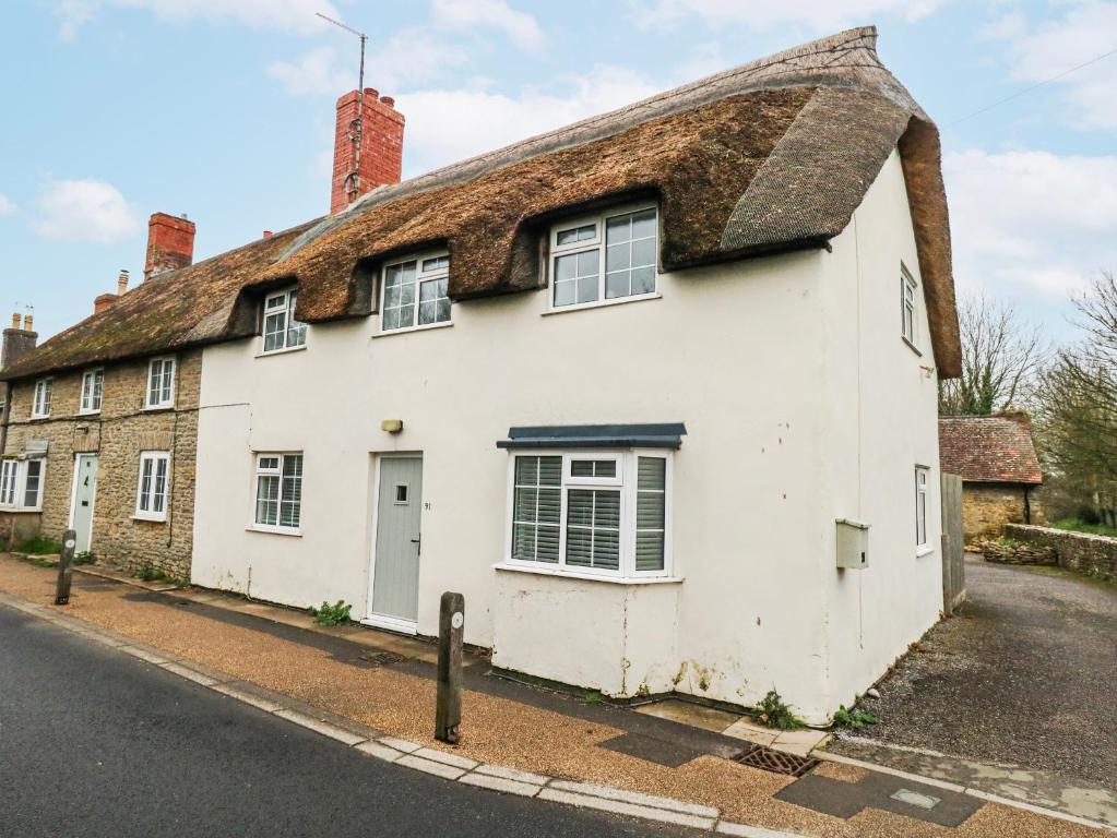 an old white house with a thatched roof at Long Barn in Bridport