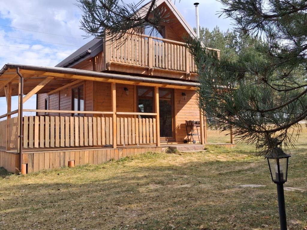 a wooden house with a porch and a tree at Domki Dębowe Wzgórze in Potok Złoty