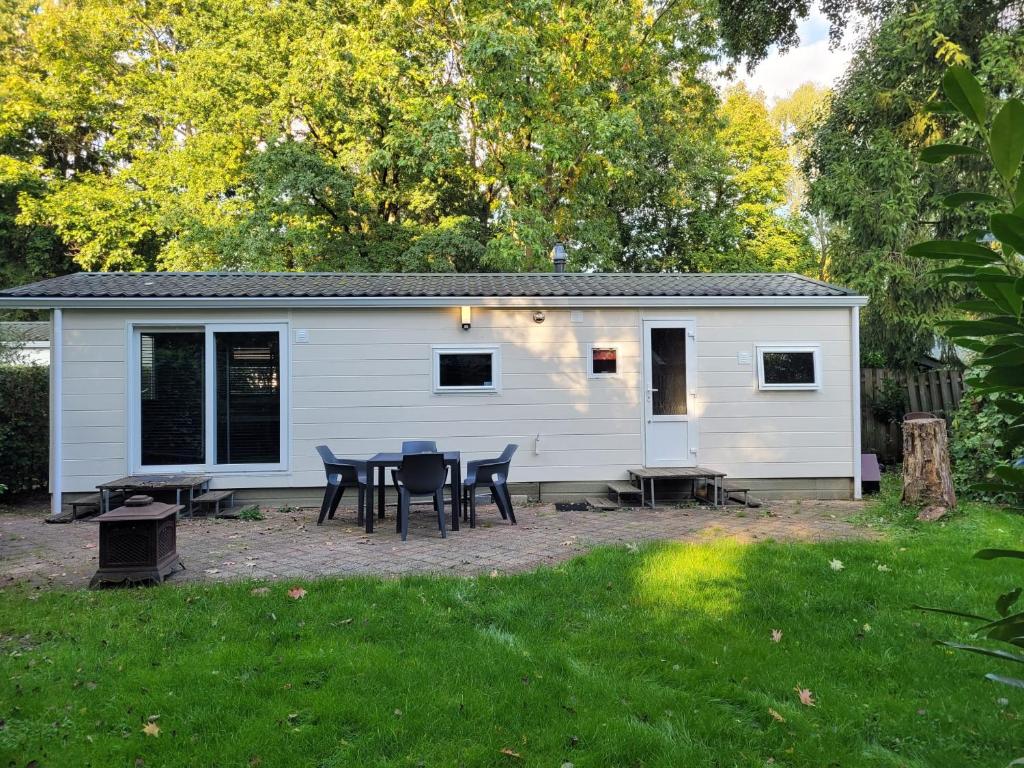 a white cabin with a table and chairs in a yard at Gezellig chalet voor gezinnen op de Veluwe I Veldkamp F16 in Epe