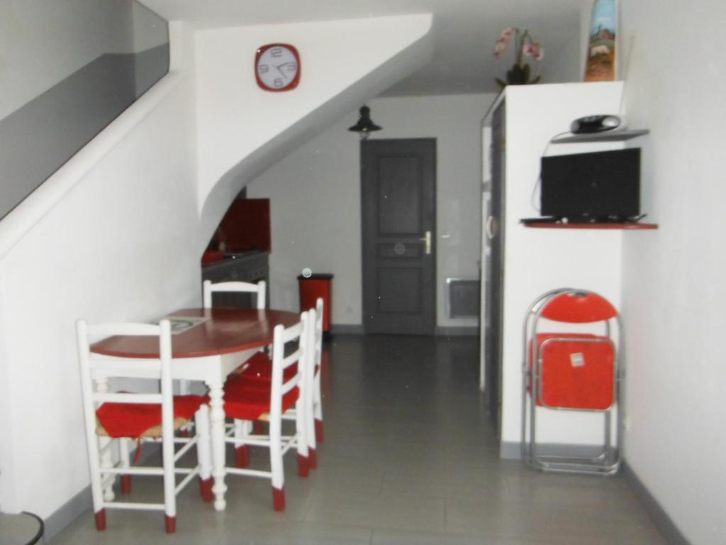 Appartement Le Romarin في مالمور: غرفة طعام مع طاولة وكراسي وساعة