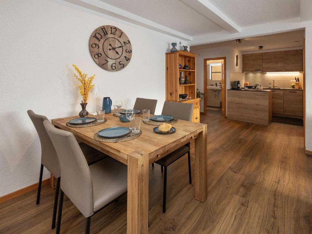a dining room table with chairs and a clock on the wall at Apartment Baroudeur B04 by Interhome in Verbier