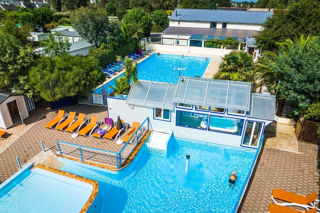an overhead view of a large swimming pool with chairs at Camping Bel Air - Cancale in Cancale