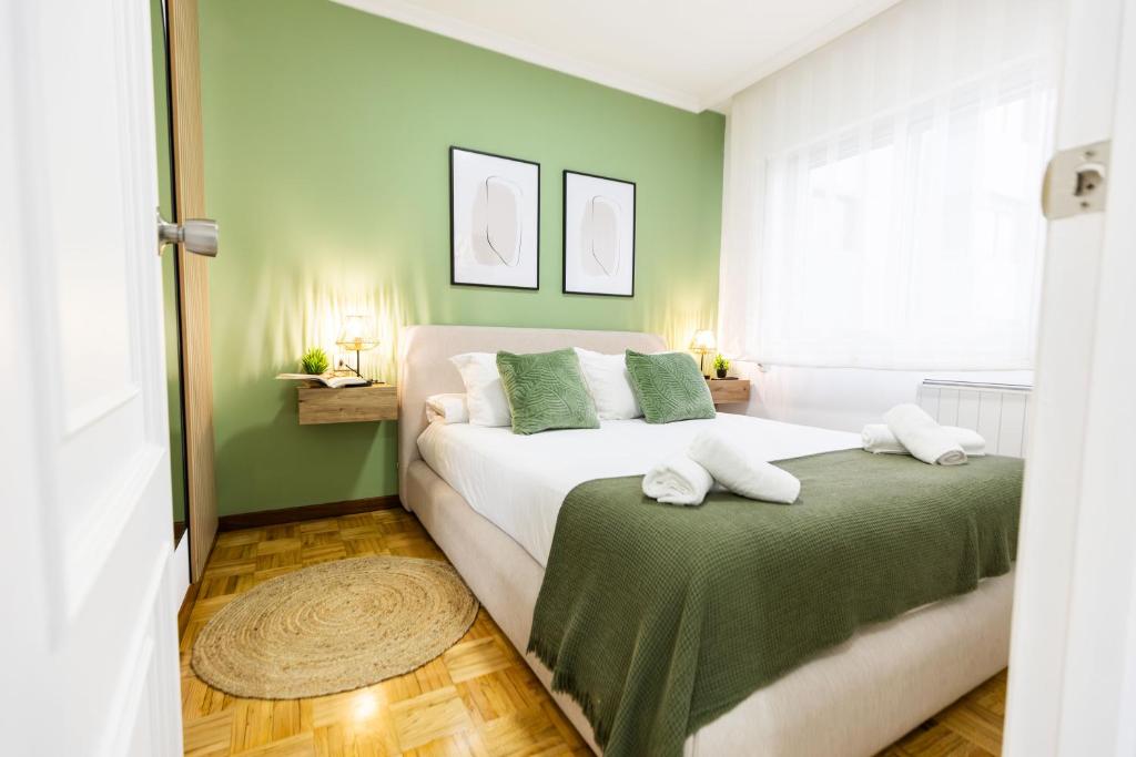 a bedroom with a large white bed with green walls at Terraza, 20min playas, 5min Pontevedra, Garaje in Pontevedra