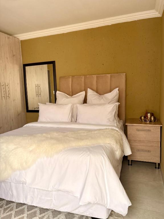 a bedroom with a large bed with white sheets and pillows at Ring Road Guesthouse in Vereeniging