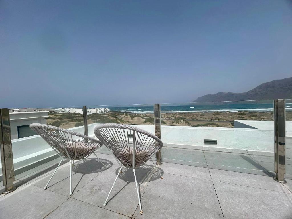 two chairs sitting on a balcony looking out at the ocean at Famara ocean view house in Famara