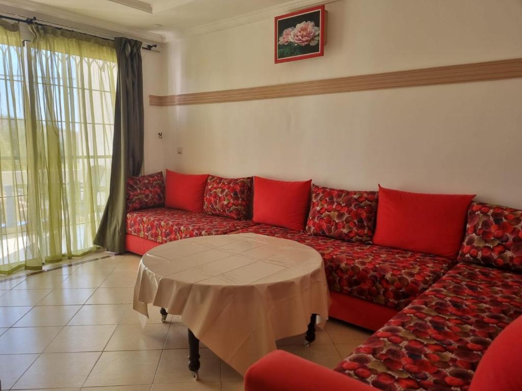a living room with a red couch and a table at Appartement Imi-Ouaddar 1 in Agadir nʼ Aït Sa