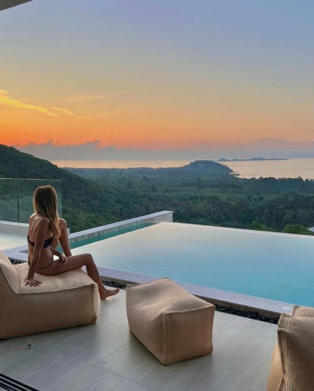 a woman sitting on a chair on the edge of a house at Sea Breeze Villa in Taling Ngam Beach