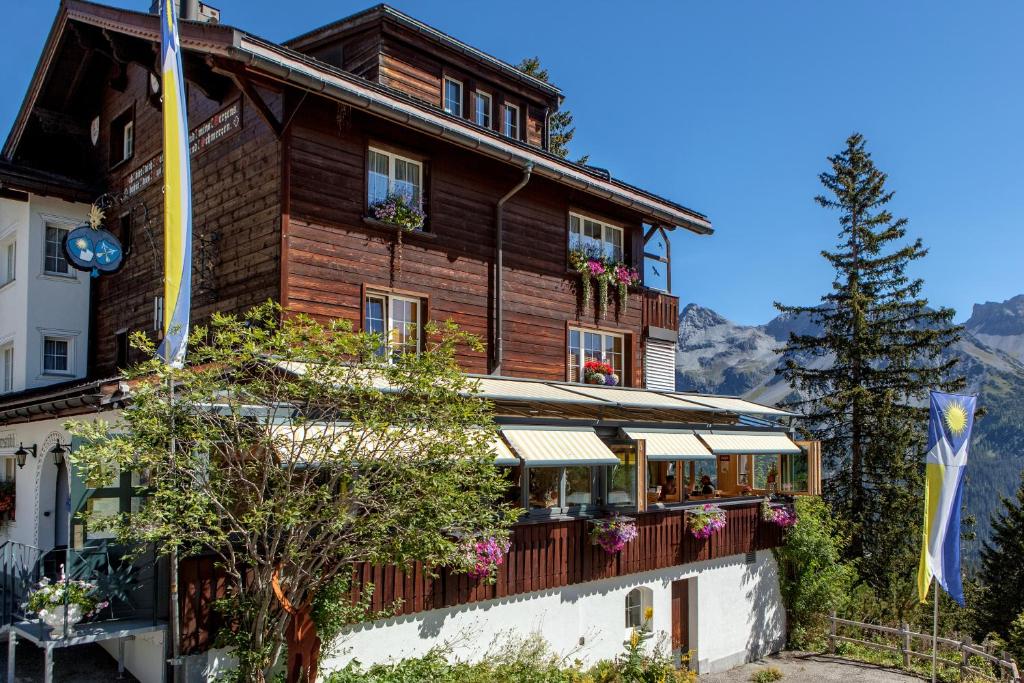 a large wooden building with flowers on the balconies at Hotel Arlenwald in Arosa