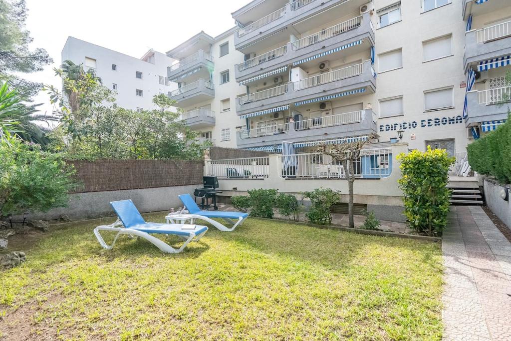 two chairs sitting on the grass in front of a building at Euma Apartment in Cunit