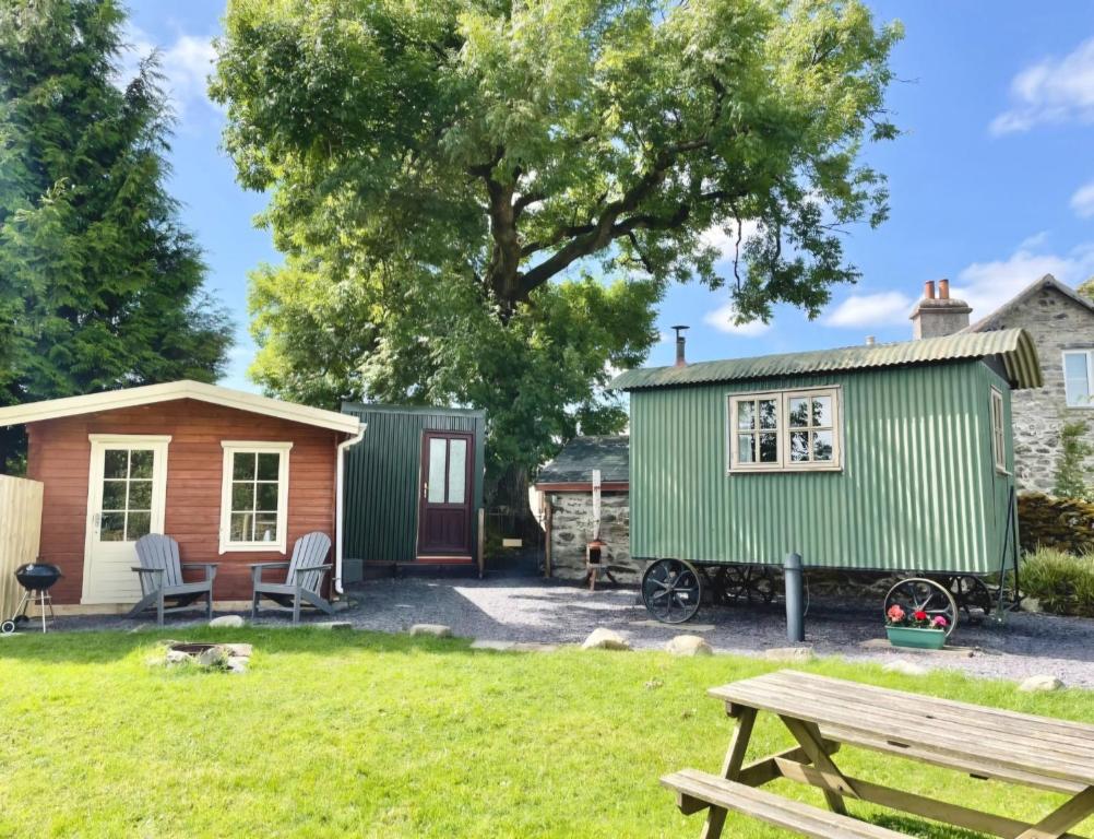 a tiny house and a shed with a picnic table at Cwt Tyddyn Shepherd's Hut in Corwen