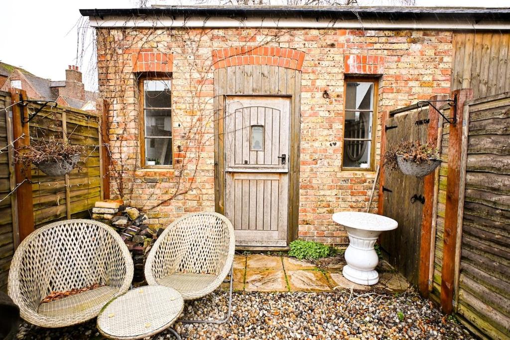 a brick building with two chairs and a door at Hope Cottage in Hythe