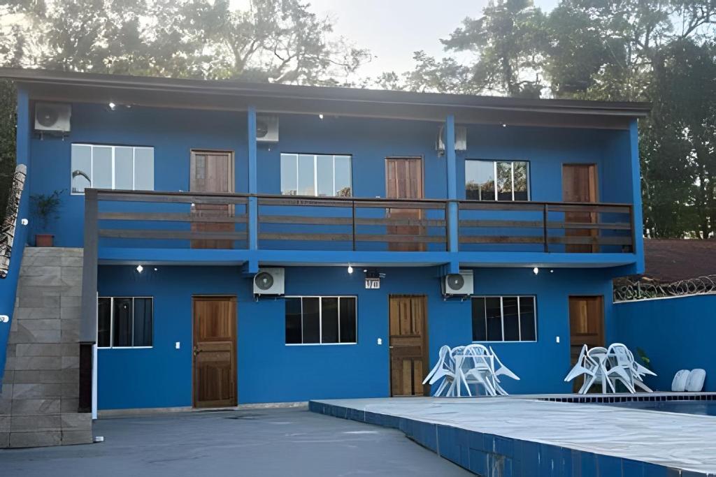 a blue house with a balcony and white chairs at Chalés do Mako in São Sebastião