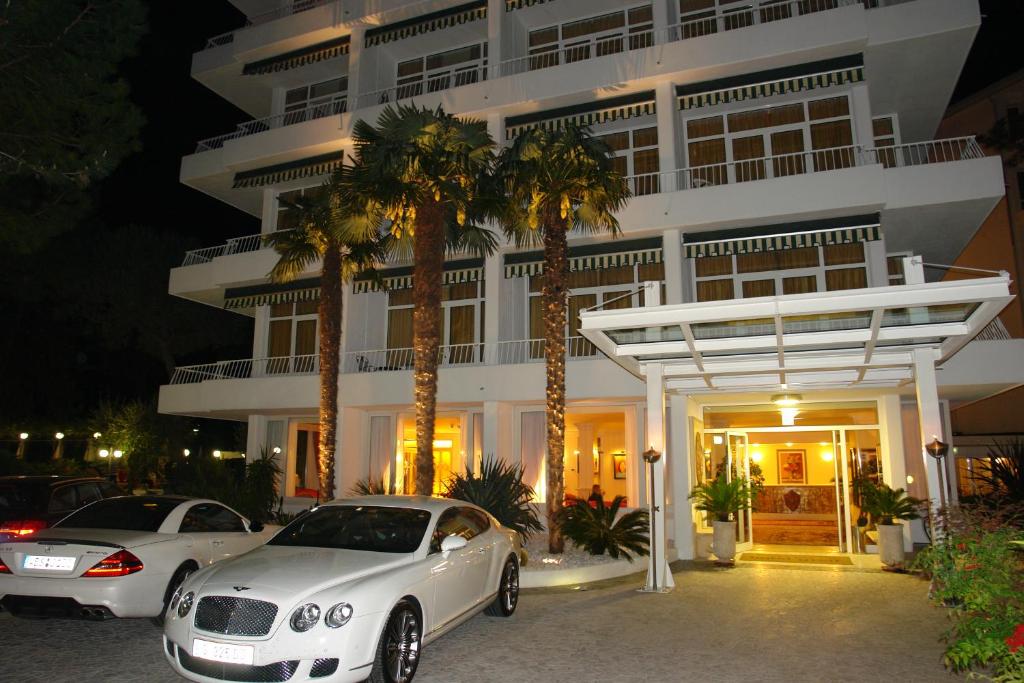 una macchina bianca parcheggiata di fronte a un edificio di Hotel Greif a Lignano Sabbiadoro
