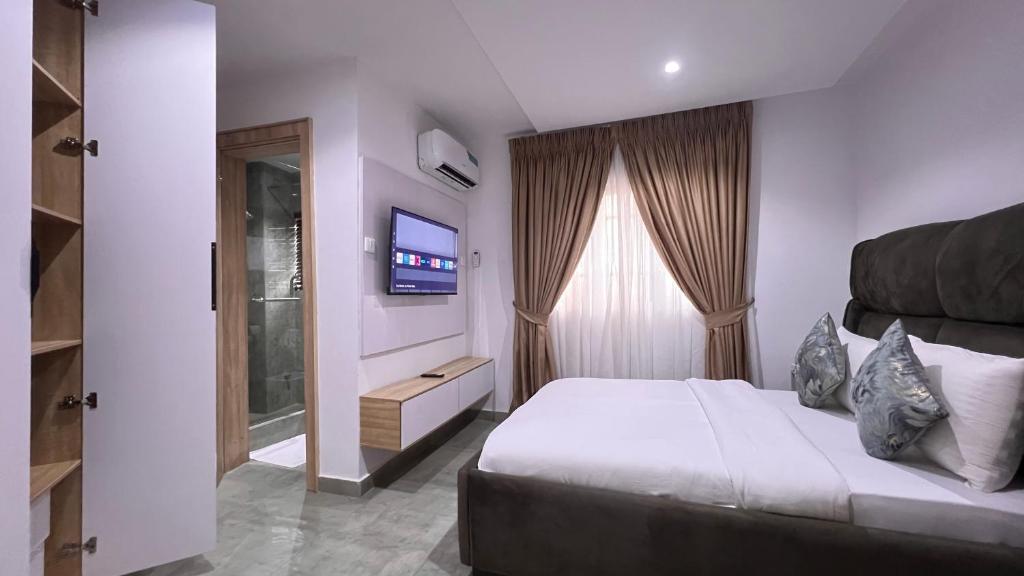 a bedroom with a large bed and a television at Hillgates Apartments Ikeja in Ikeja