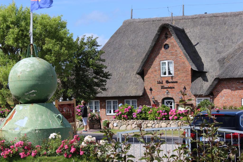 ein großes Haus mit einem Strohdach und einer Statue in der Unterkunft Ual Öömrang Wiartshüs in Norddorf